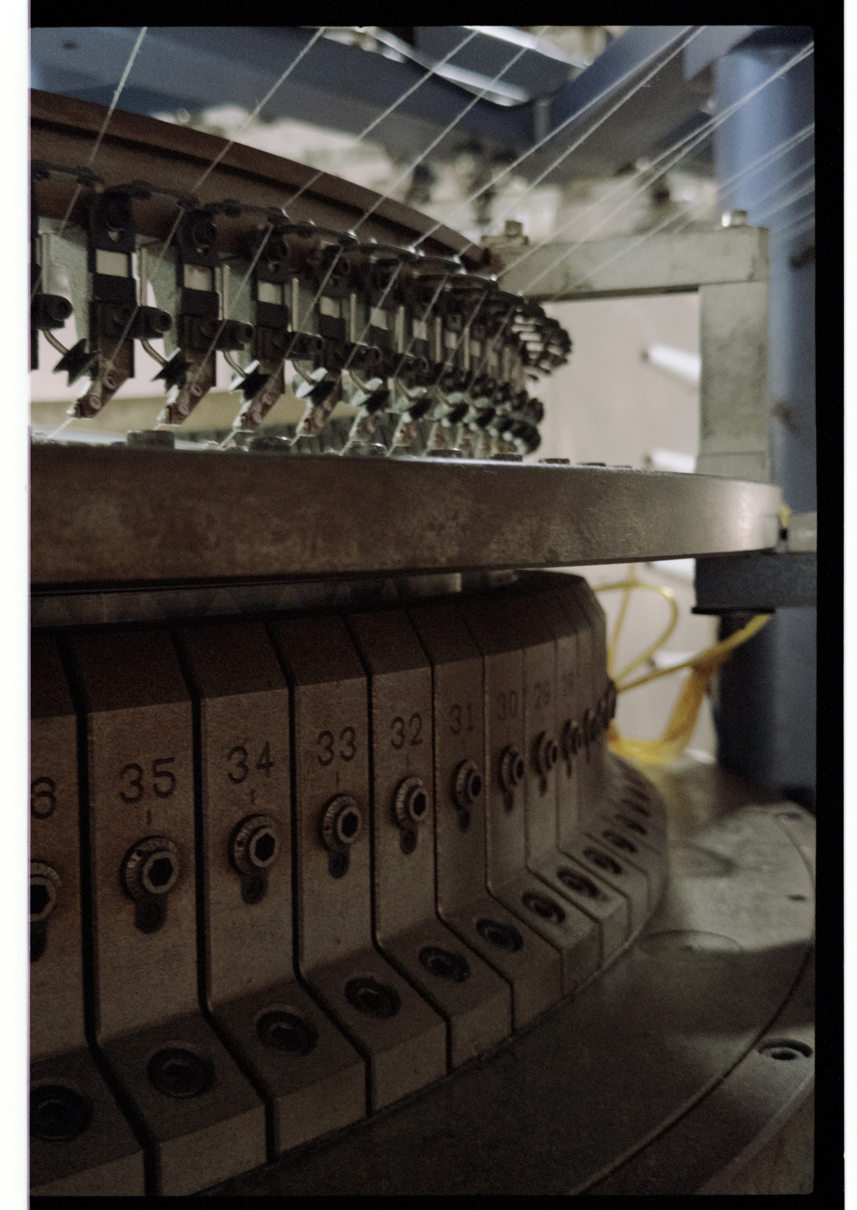 Circular knitting machine detail showing yarn paths, feeding components, and numbered machine sections.