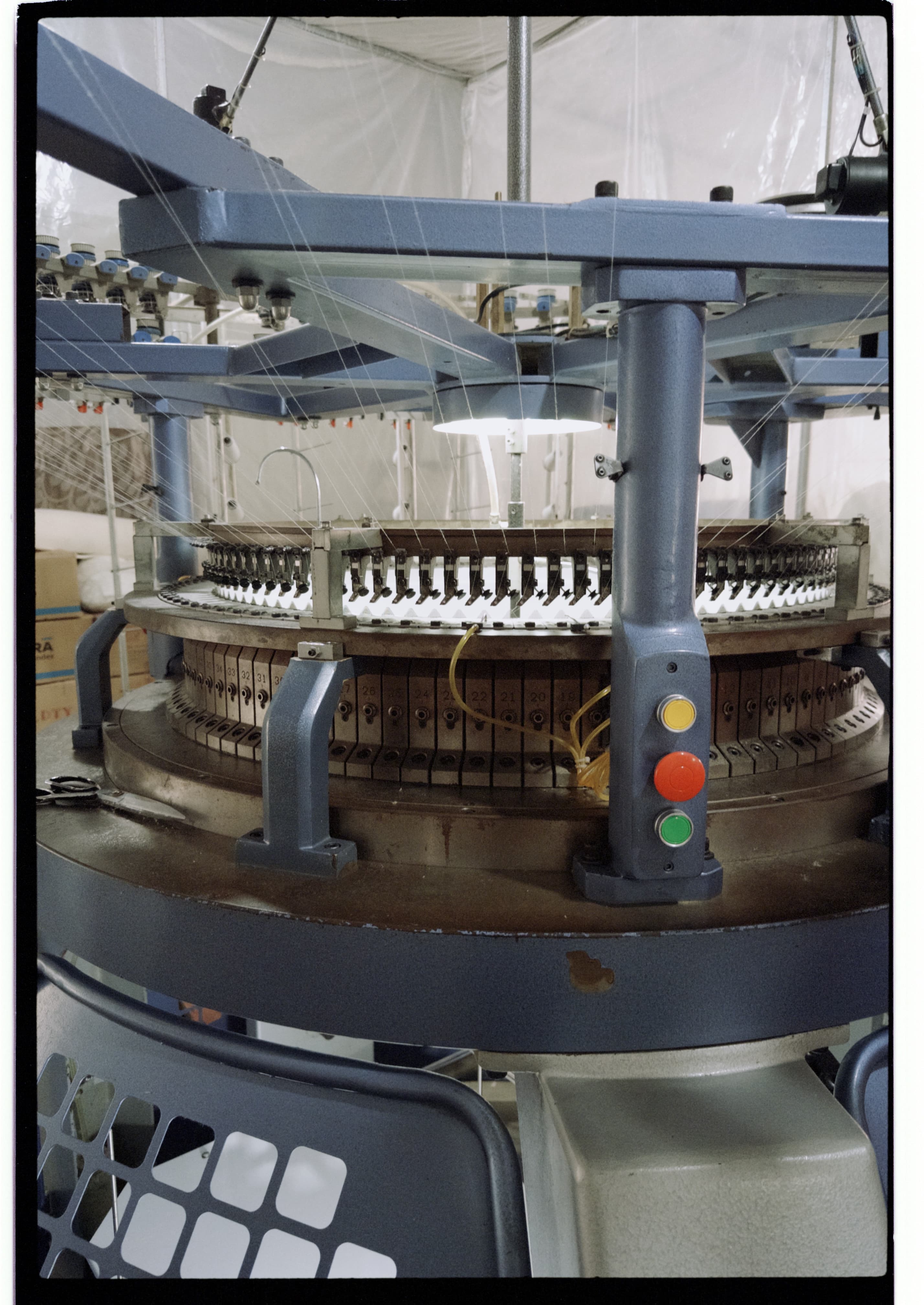 Circular knitting machine photographed during a mill visit, showing the machine frame, yarn paths, and knitting area.