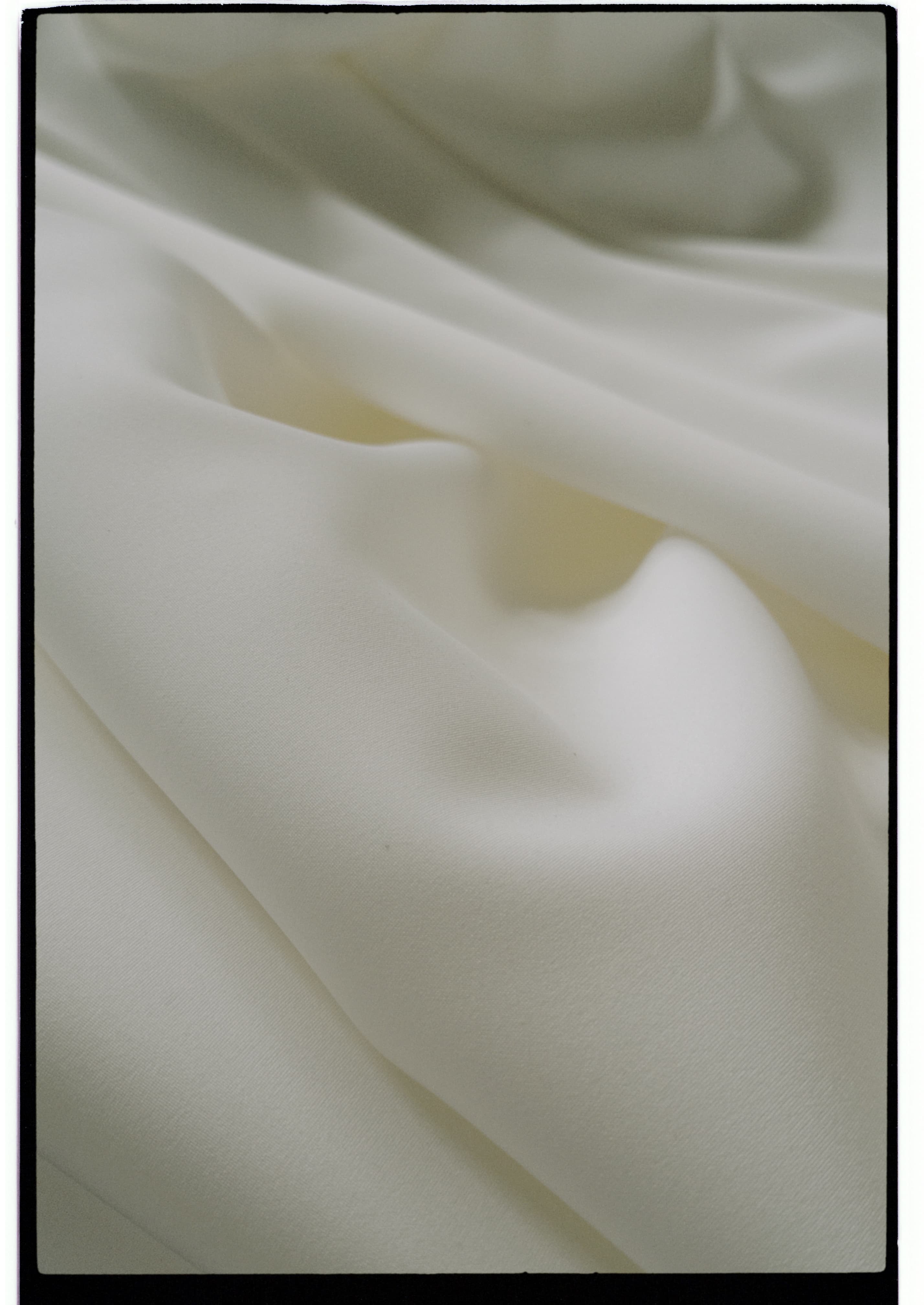 Close-up of ivory knitted fabric with fine surface texture and softly draped folds, photographed during a dyehouse visit.