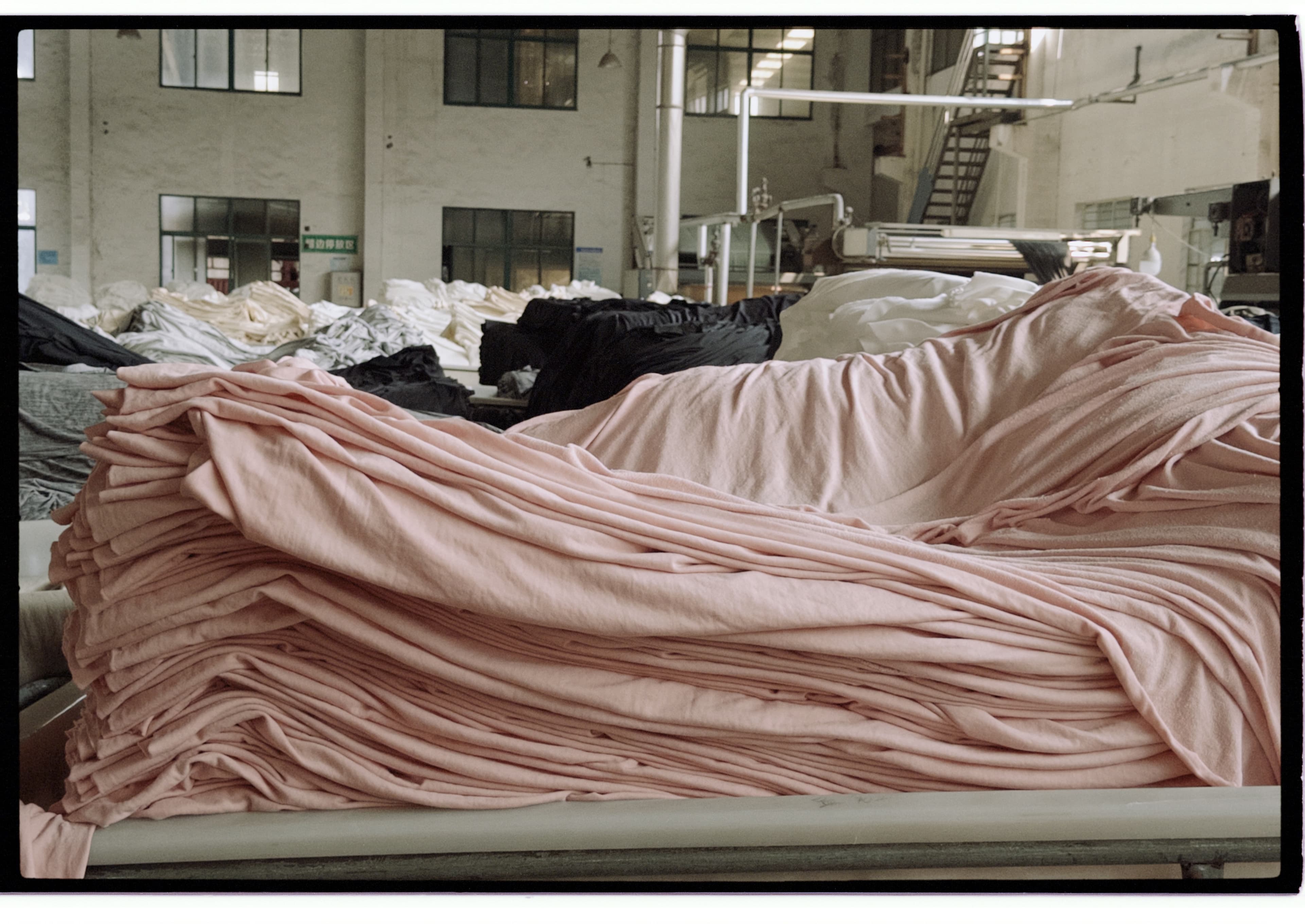 Soft pink fabric gathered in layered folds inside a dyehouse.