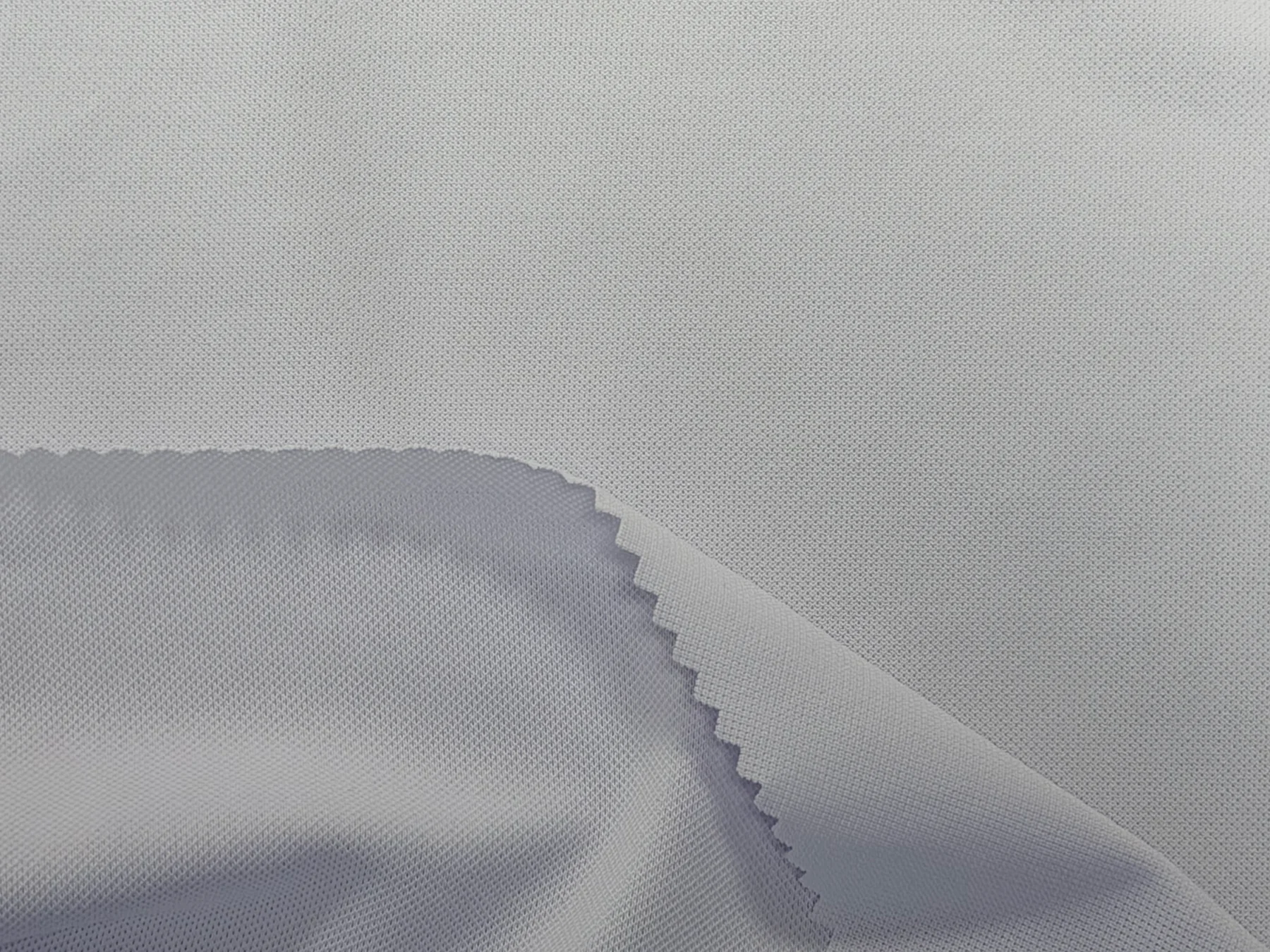 Light grey polyester-spandex piqué knit swatches, with a folded edge revealing the fabric texture on both sides.