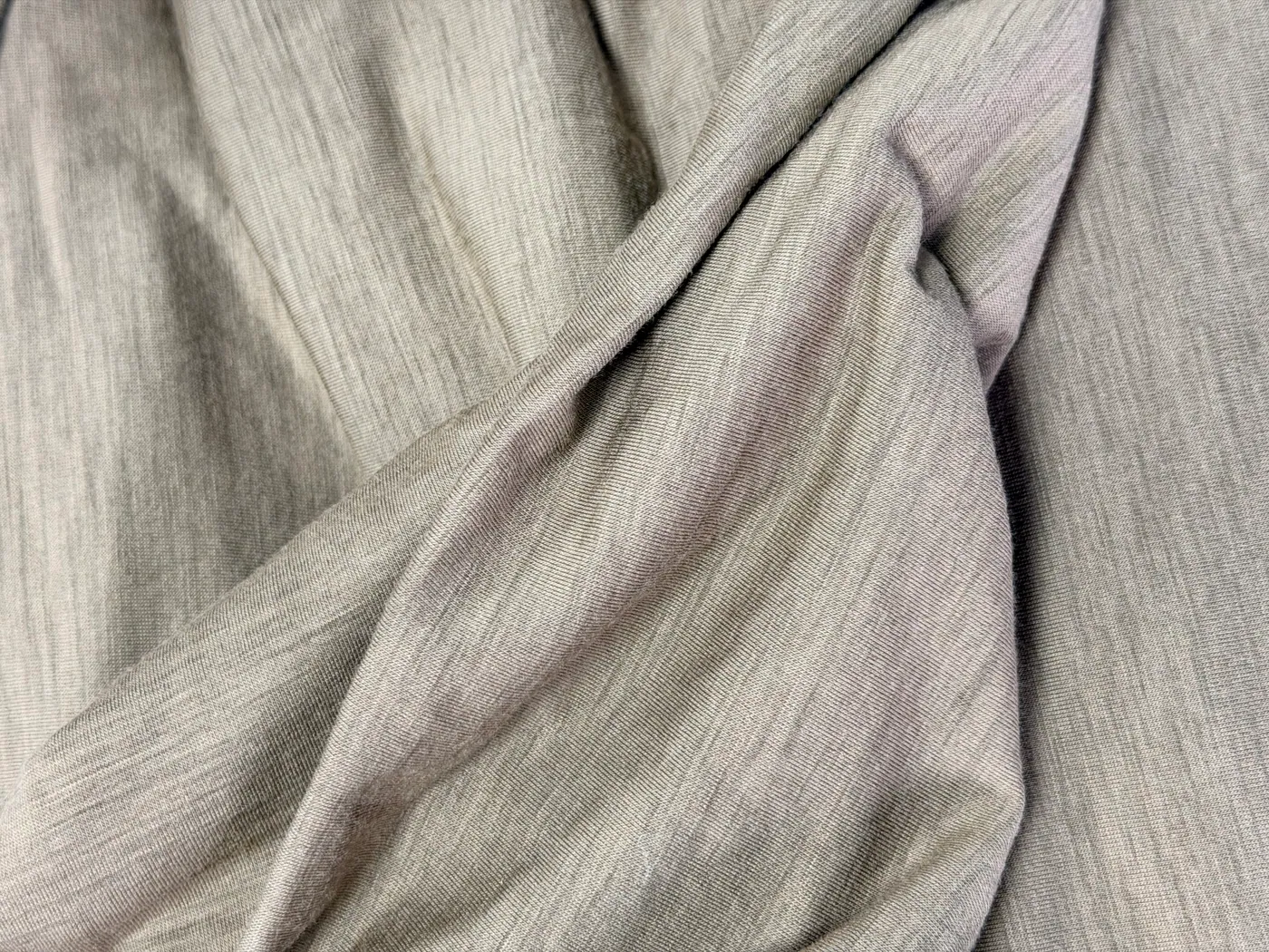 Close-up photograph of grey wool-nylon stretch jersey with fine knit loops and soft folds.