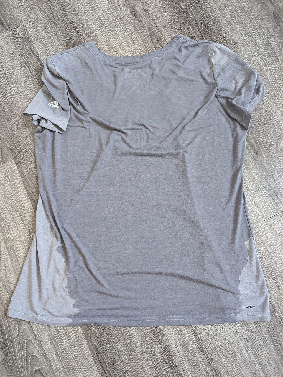 A grey T-shirt with a darker sweat-wetted centre and lighter dry fabric along the sides, showing the wet–dry colour contrast.
