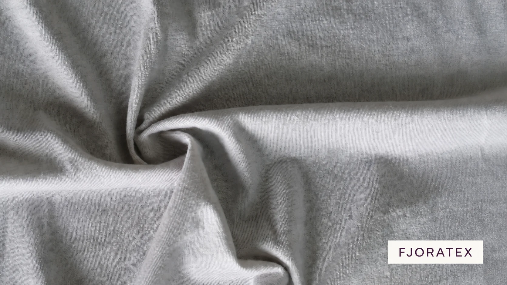 Light grey knitted fabric arranged in soft folds, with the purple FJORATEX wordmark.